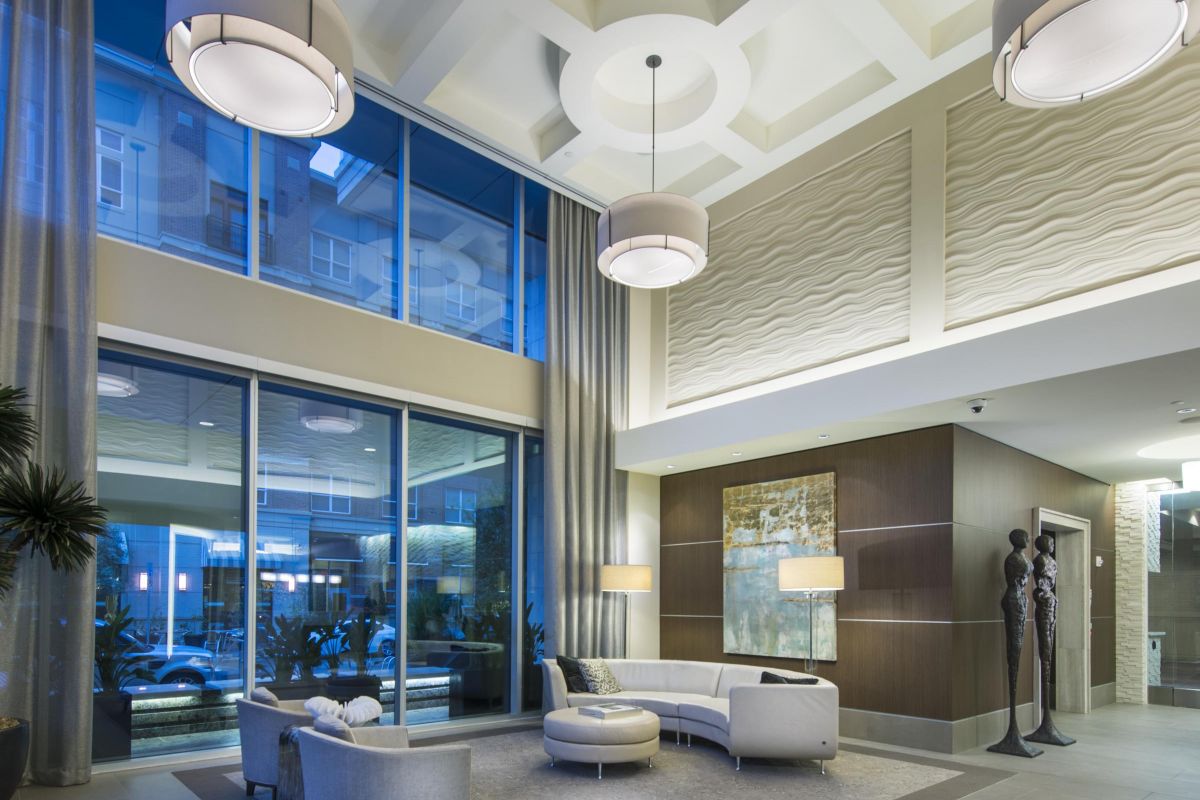 Modern lobby with tall ceilings, large windows, elegant seating, abstract art, and decorative sculptures.