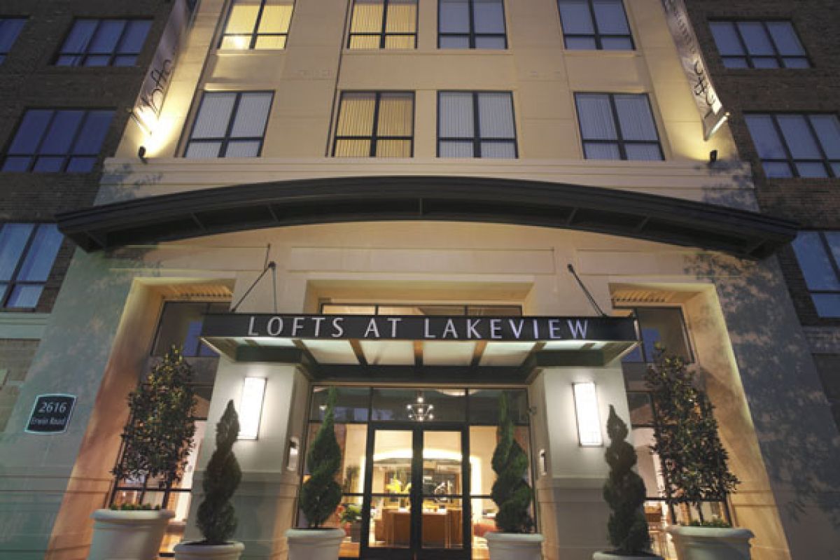 Modern apartment building entrance at night with "Lofts at Lakeview" sign above glass doors.
