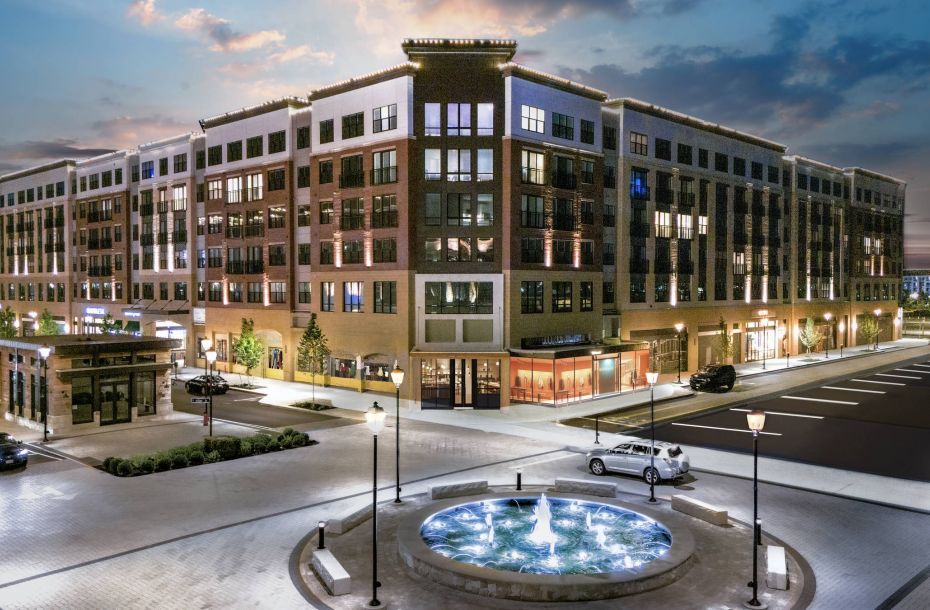 Hanover Company, Hanover Toscana Modern building complex at dusk with lit windows and a central fountain in the foreground.