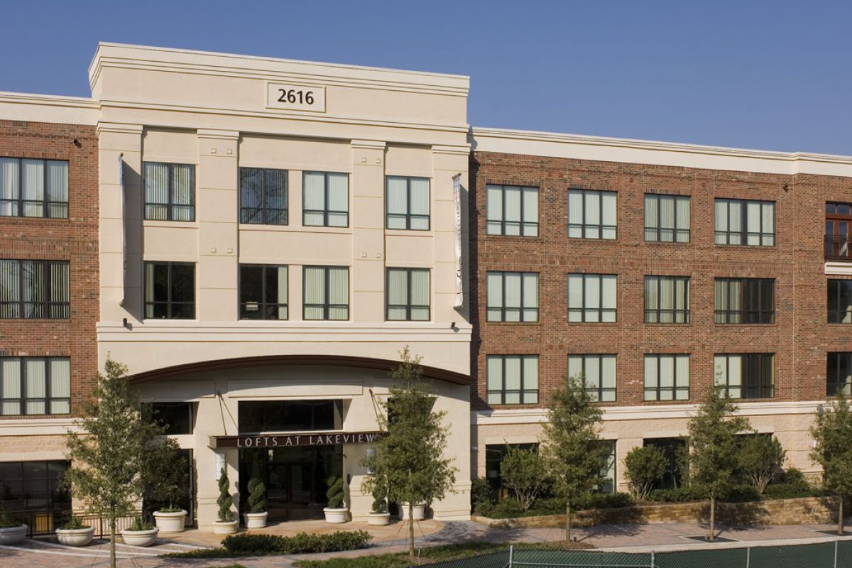 Four-story brick and stucco apartment building with large windows, labeled "Lofts at Lakeview" at entrance.
