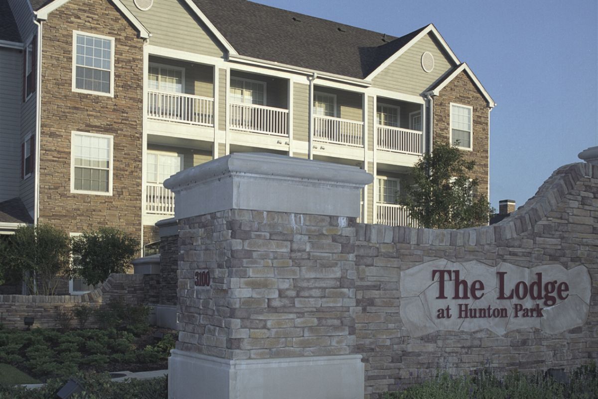 A modern apartment building behind a stone sign that reads "The Lodge at Hunton Park.