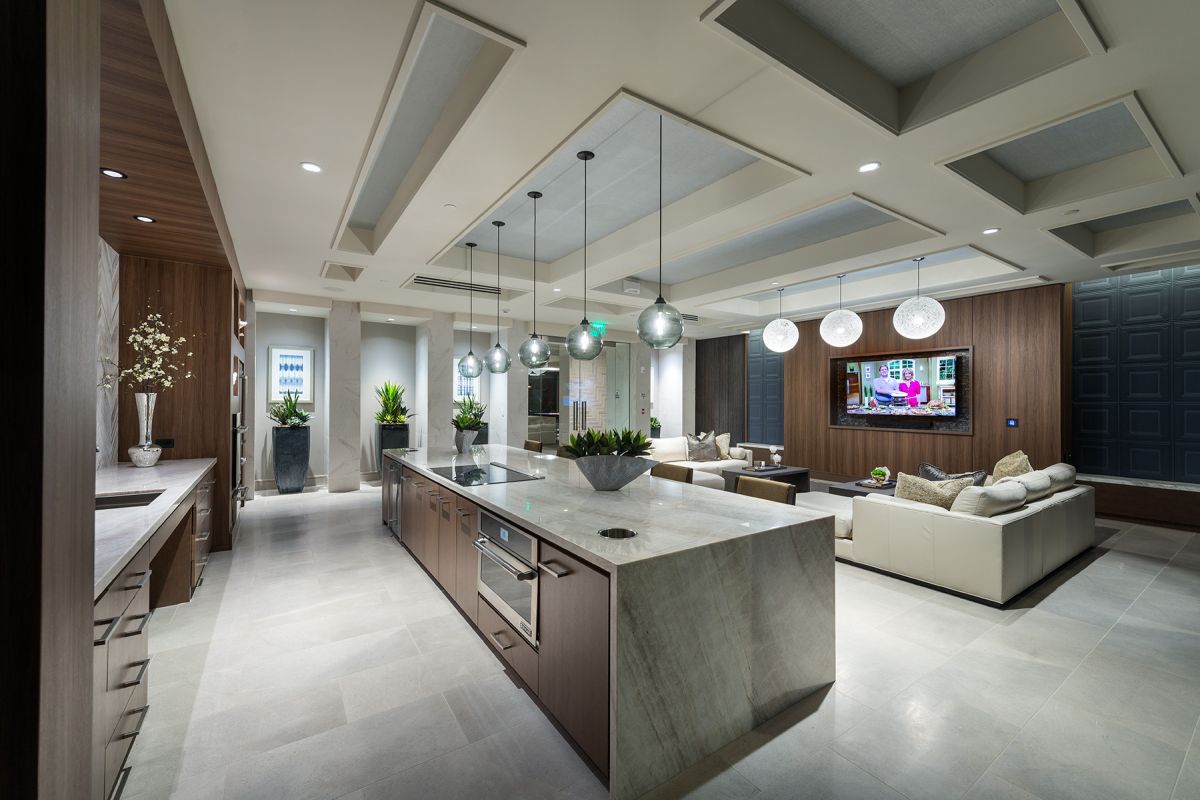 Modern open-concept kitchen and living room with pendant lights, marble island, and neutral decor.