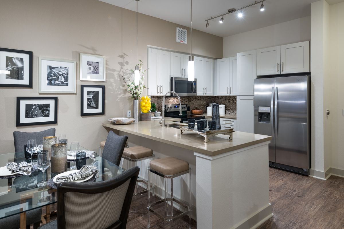 Modern kitchen with white cabinets, stainless steel appliances, and a dining table set for four.
