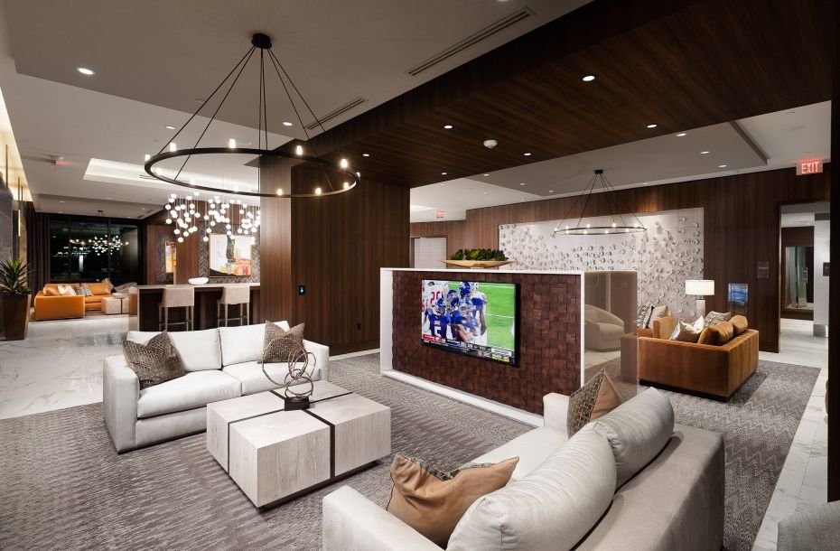 Hanover Company, Hanover River Oaks Modern lounge with sofas, a TV, and dining area. Elegant decor, soft lighting, and marble flooring.