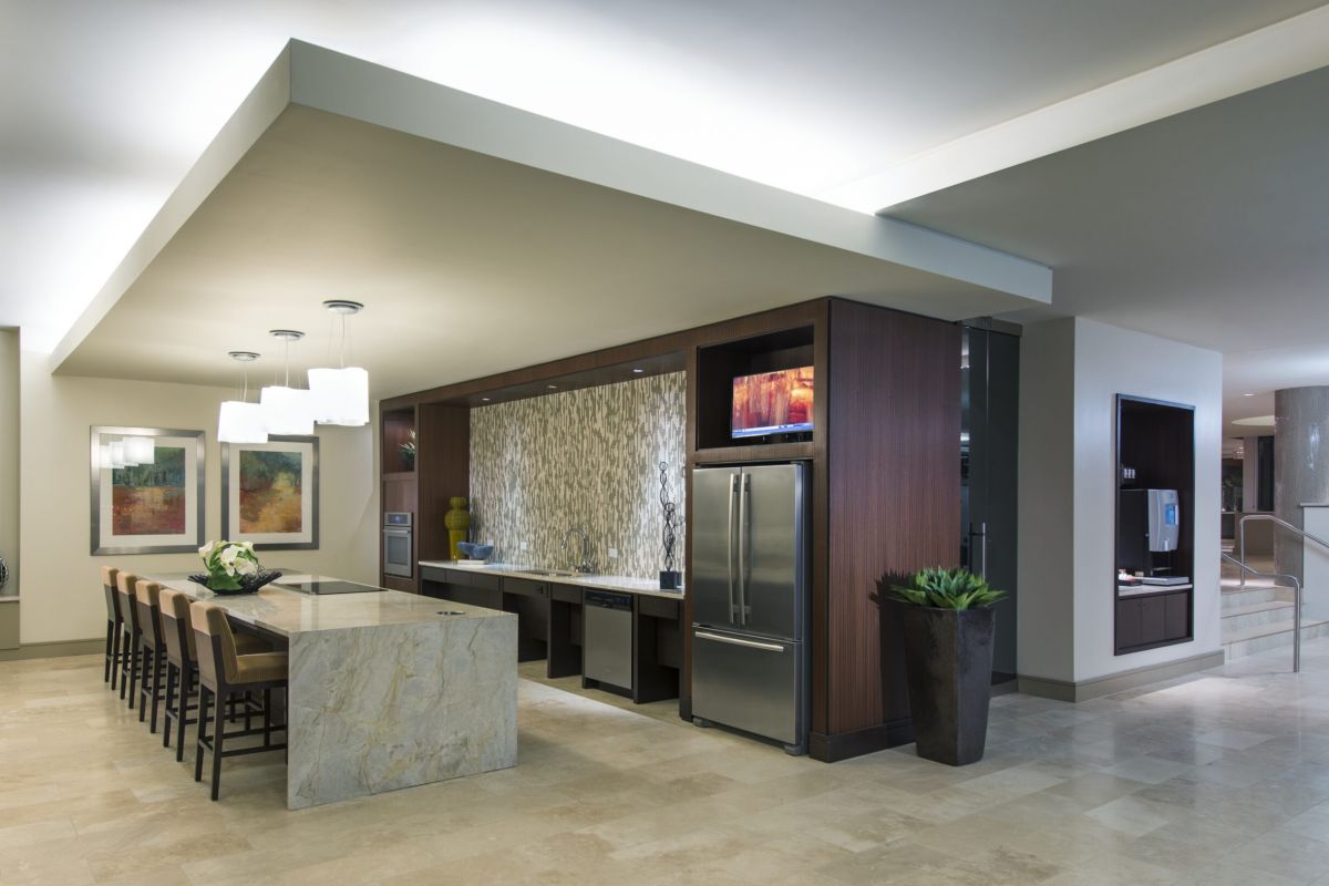 Modern kitchen with marble island, bar stools, stainless steel fridge, and decorative wall art.