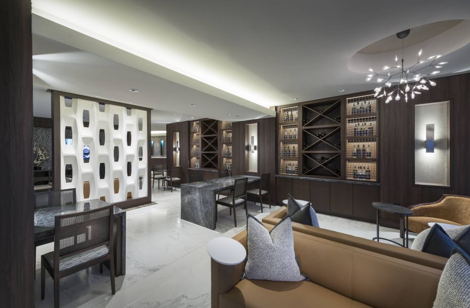 Hanover Company, Hanover Buckhead Village Modern lounge with sleek furniture, dim lighting, a patterned wall, and wine racks on display.