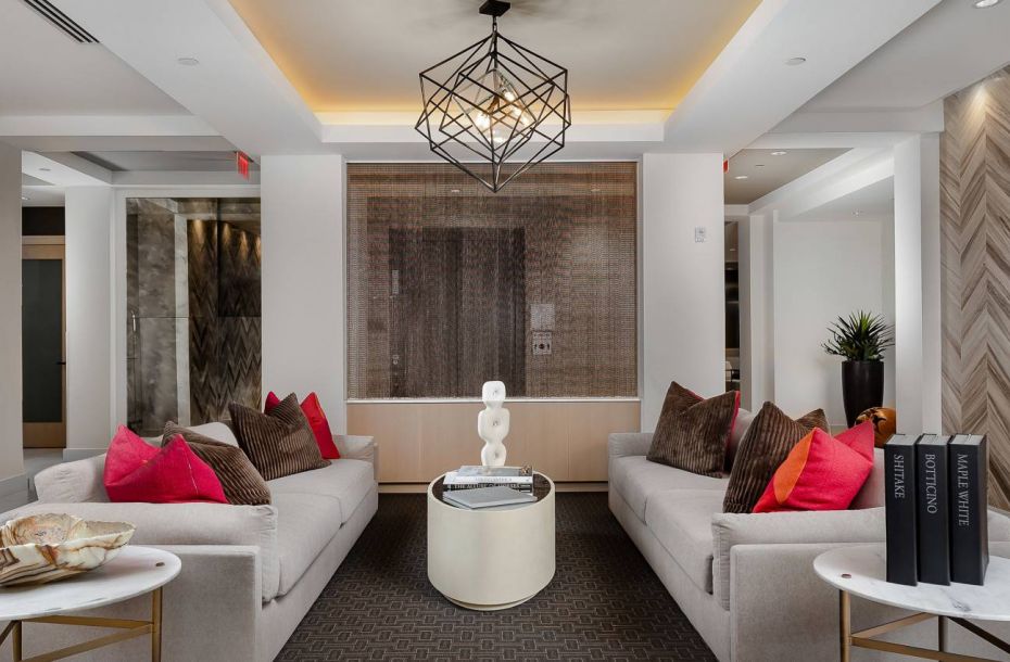 Hanover Company, Hanover Tuscan Village Modern living room with two beige sofas, colorful pillows, a geometric chandelier, and a fireplace.