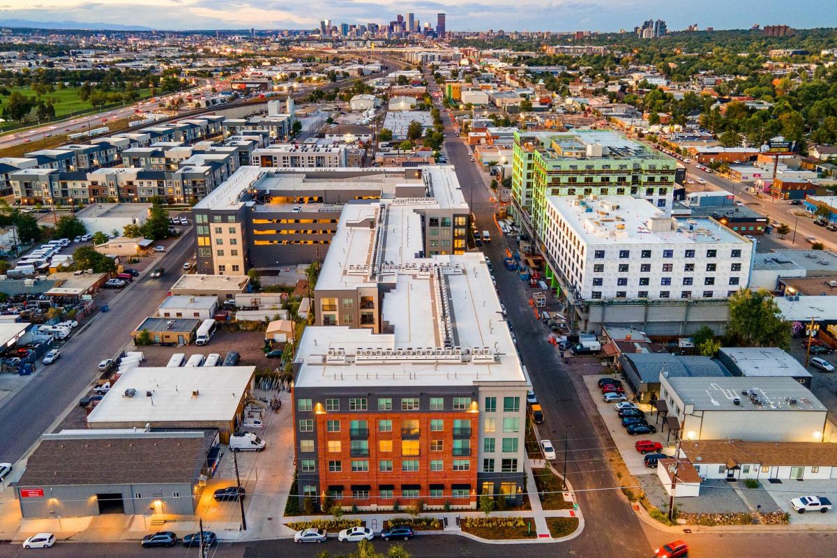 Aerial view of an urban neighborhood with a mix of residential and commercial buildings under a cloudy sky.