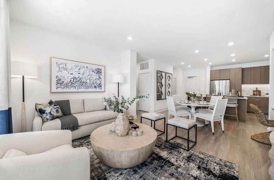 Hanover Company, Hanover Weymouth Modern living room with a beige sofa, abstract art, round coffee table, dining area, and open kitchen in the background.
