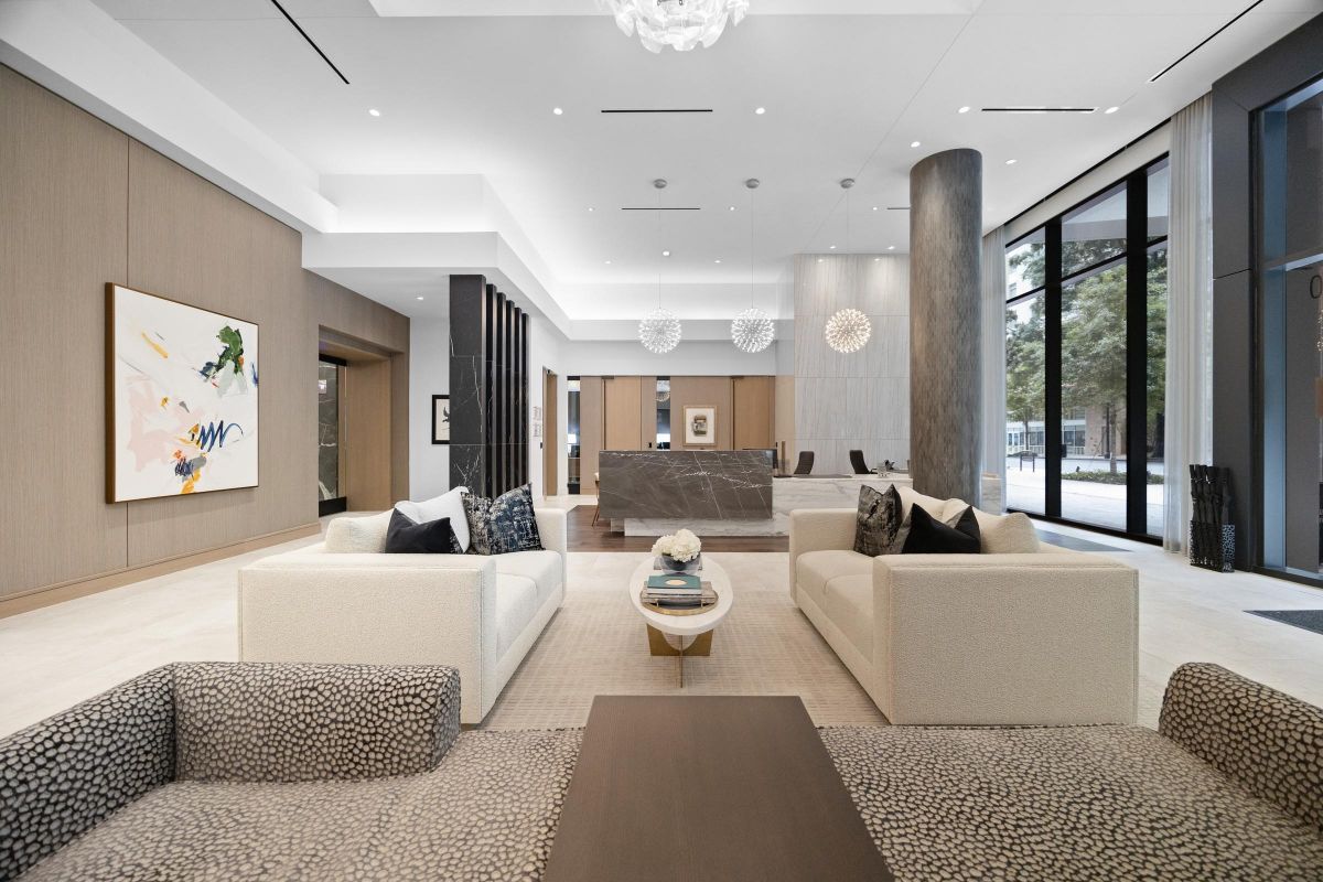 Modern lobby with two beige sofas, abstract art, a wooden coffee table, and large windows providing natural light.
