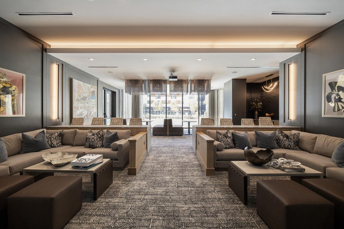 Modern lounge with gray sofas, art on the walls, low tables, and large windows letting in natural light.