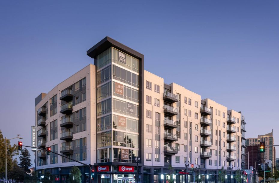 Hanover Company, Hanover Broadway Street view of a modern apartment building with retail stores on the ground level, including brightly lit entrances.