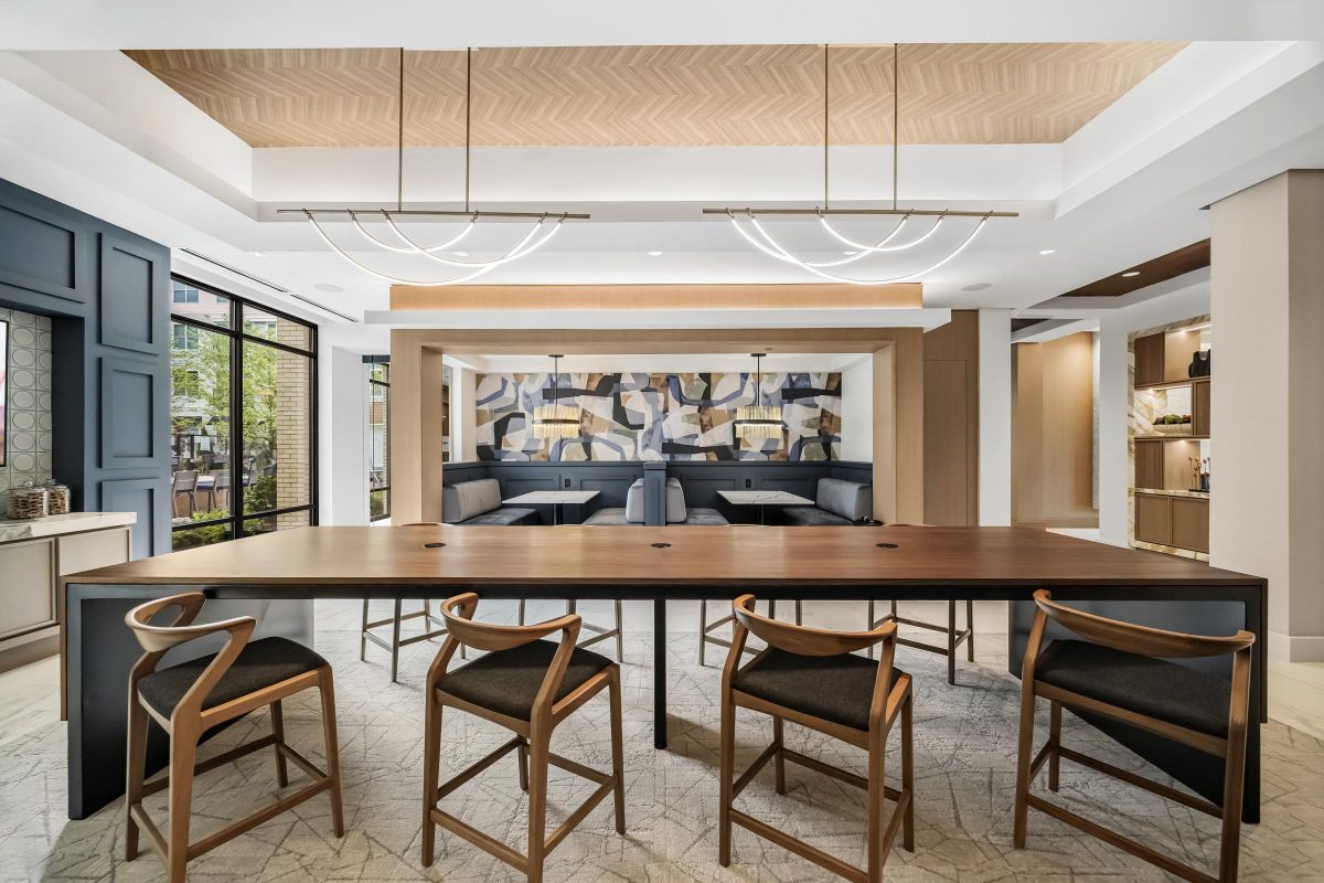 Modern dining area with wooden table, chairs, geometric wall art, and contemporary lighting fixtures.