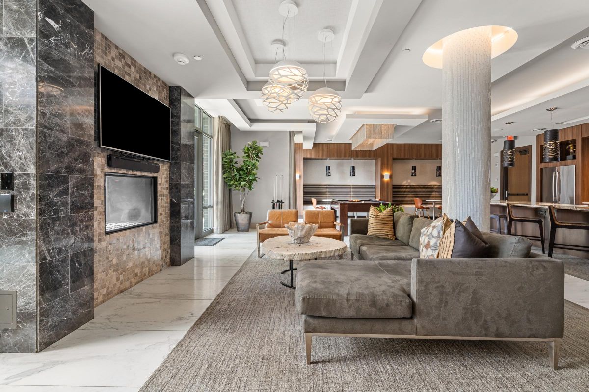 Modern lounge with sofas, TV, decorative lights, and a kitchen area in the background.