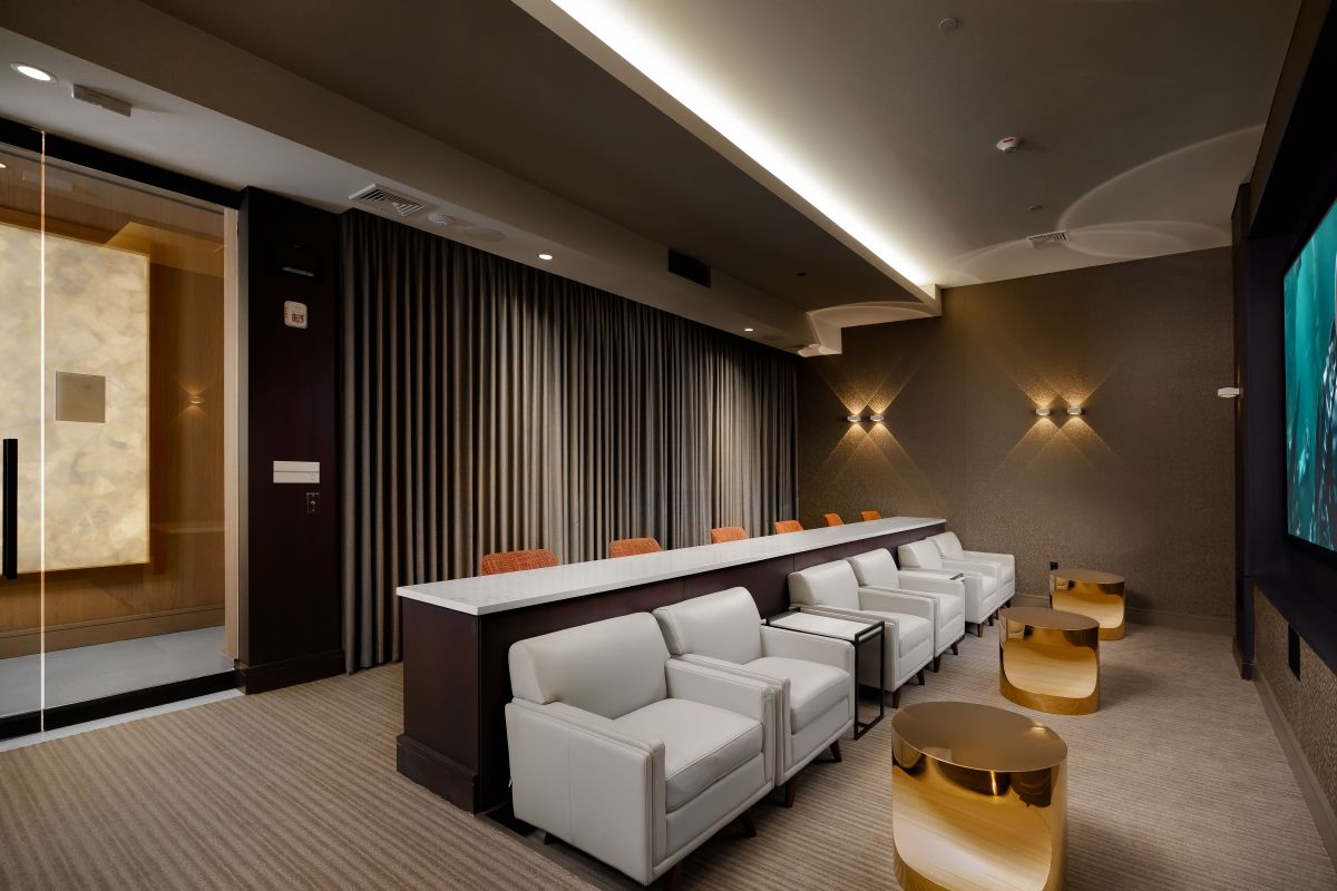 Modern Hanover screening room with white chairs, marble counter, gold tables, and a large screen showing Mystic River.