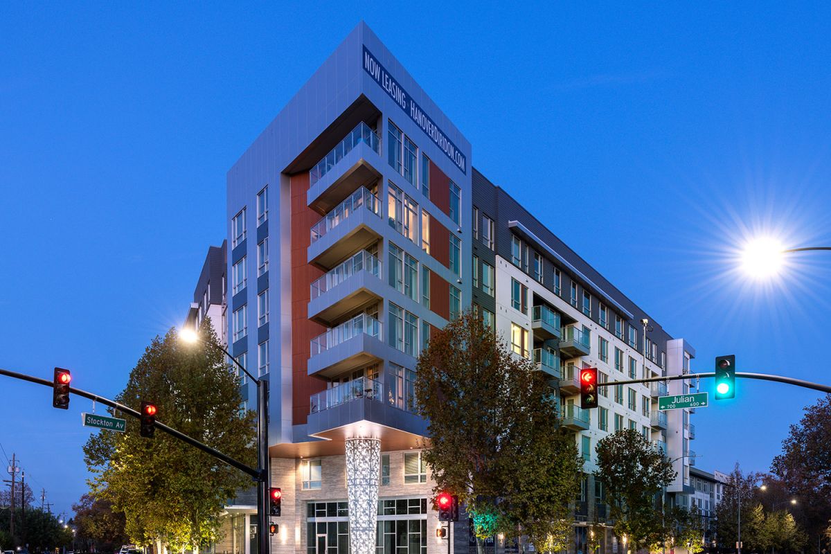 Modern multi-story San Jose apartments at dusk, with streetlights and traffic signals highlighting luxury living at Hanover Diridon.