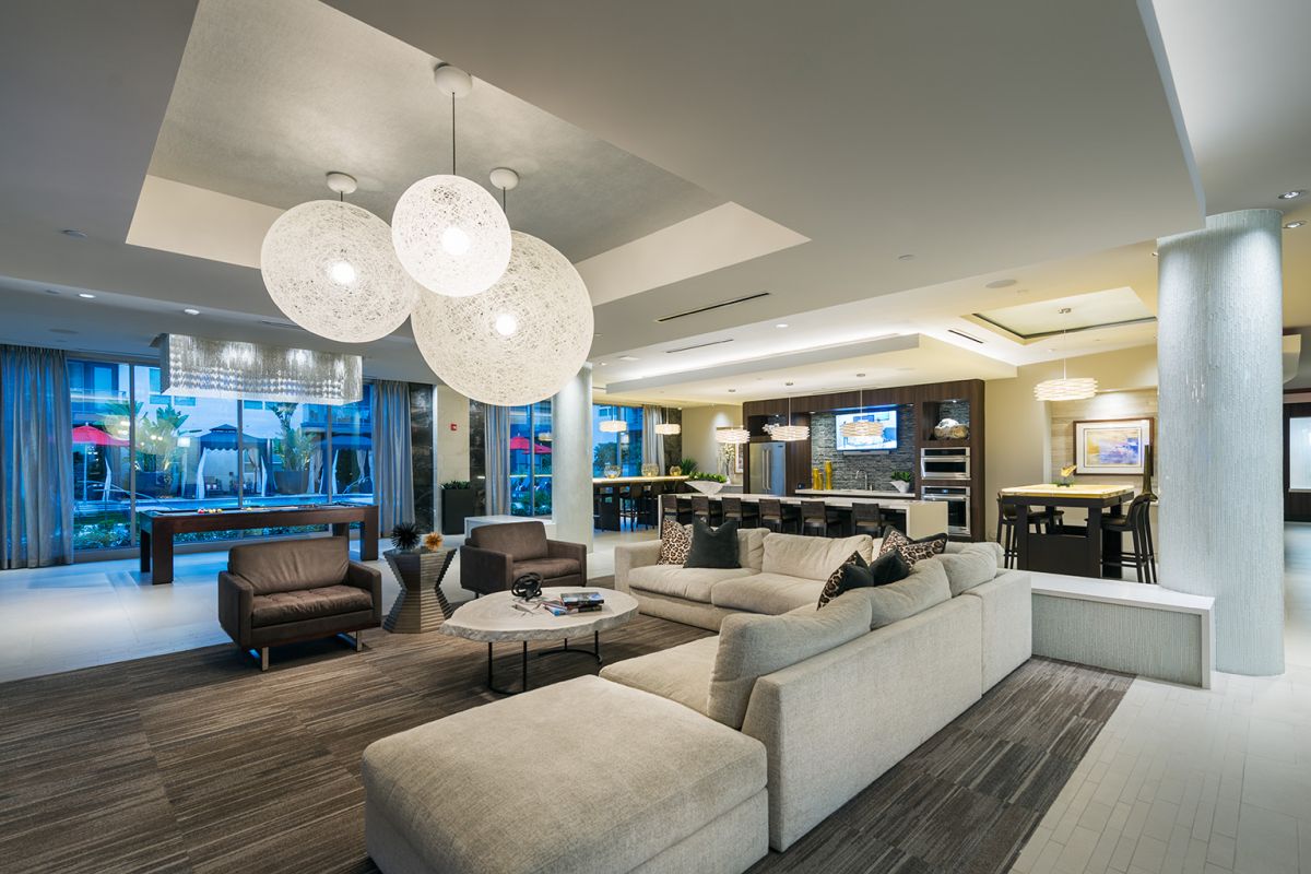 Modern open-concept living area with a beige sofa, round lights, and kitchen in the background.