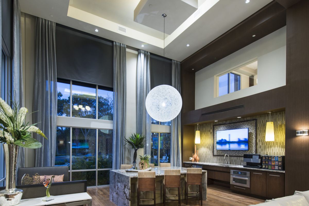 Modern open-concept living room and kitchen with high ceilings, large windows, and contemporary decor.