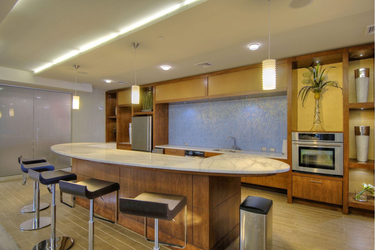 Modern kitchen with a marble island, bar stools, stainless steel appliances, and decorative accents.