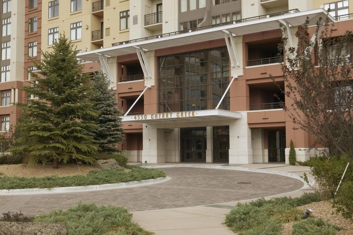 A modern apartment building entrance with glass doors and "4550 Cherry Creek" above the entryway.