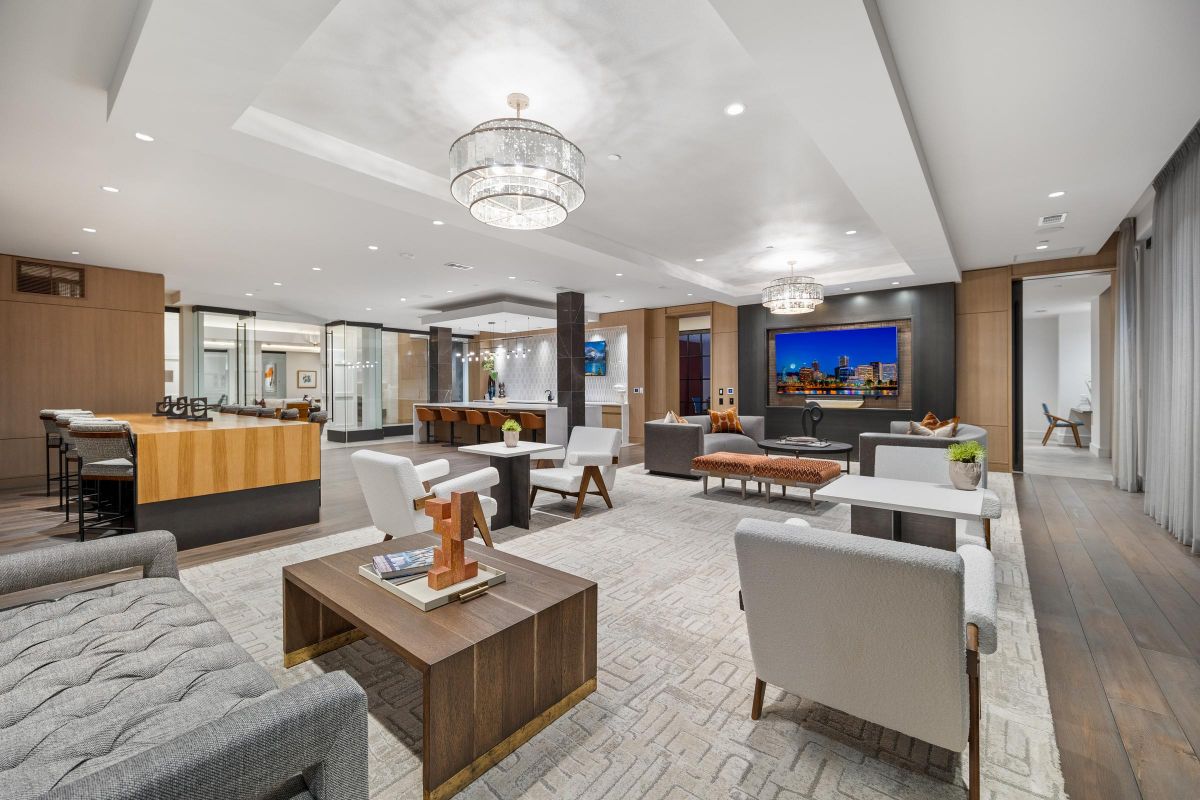 Modern lounge with sofas, tables, a TV, and chandeliers, featuring neutral tones and contemporary decor.