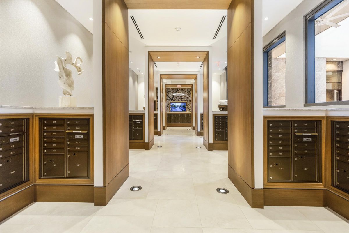 Modern interior with wooden accents, marble flooring, wall art, and large windows in a symmetrical hallway.