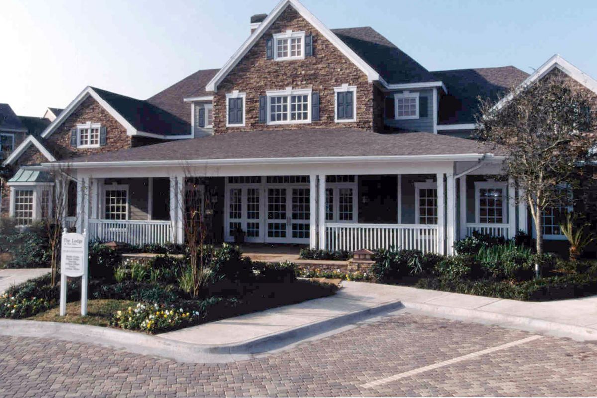 Large two-story house with stone facade, white trim, and wide porch near Churchill on the Park Dallas apartments.