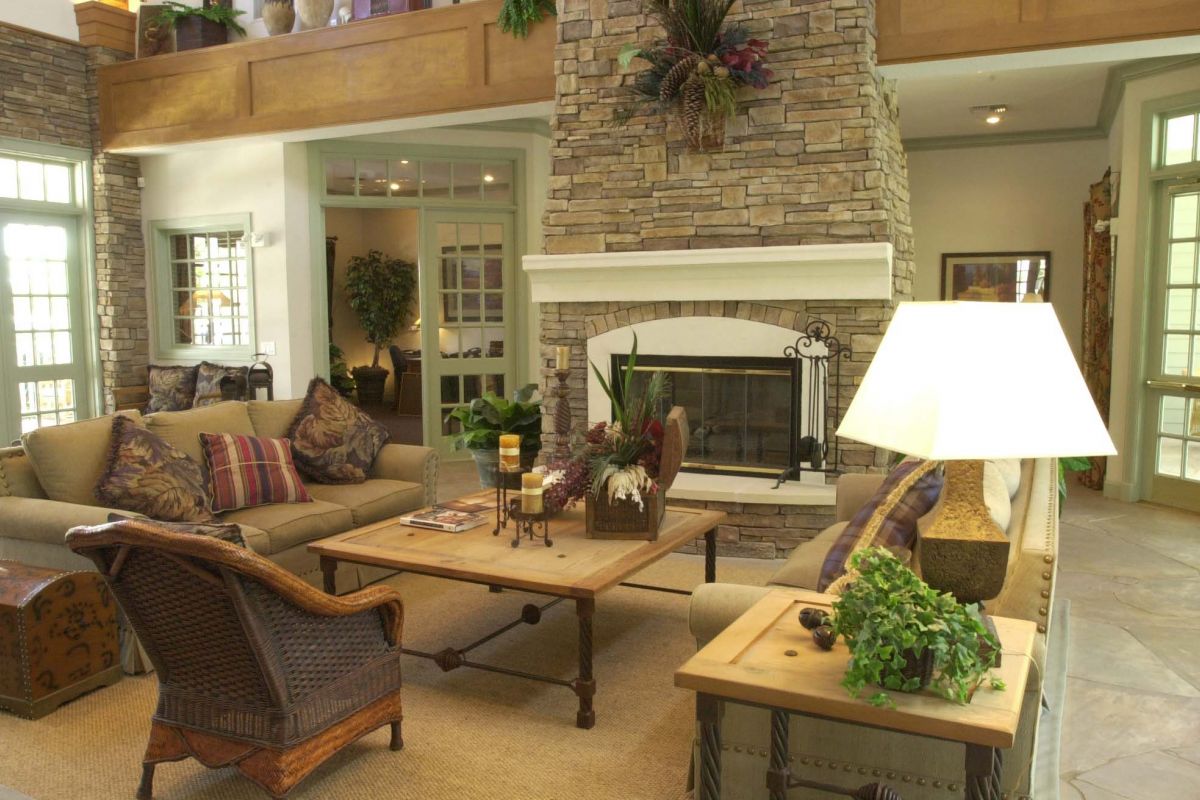 Cozy living room at Churchill on the Park apartments in Dallas, featuring sofas, a wooden coffee table, stone fireplace, and large windows.