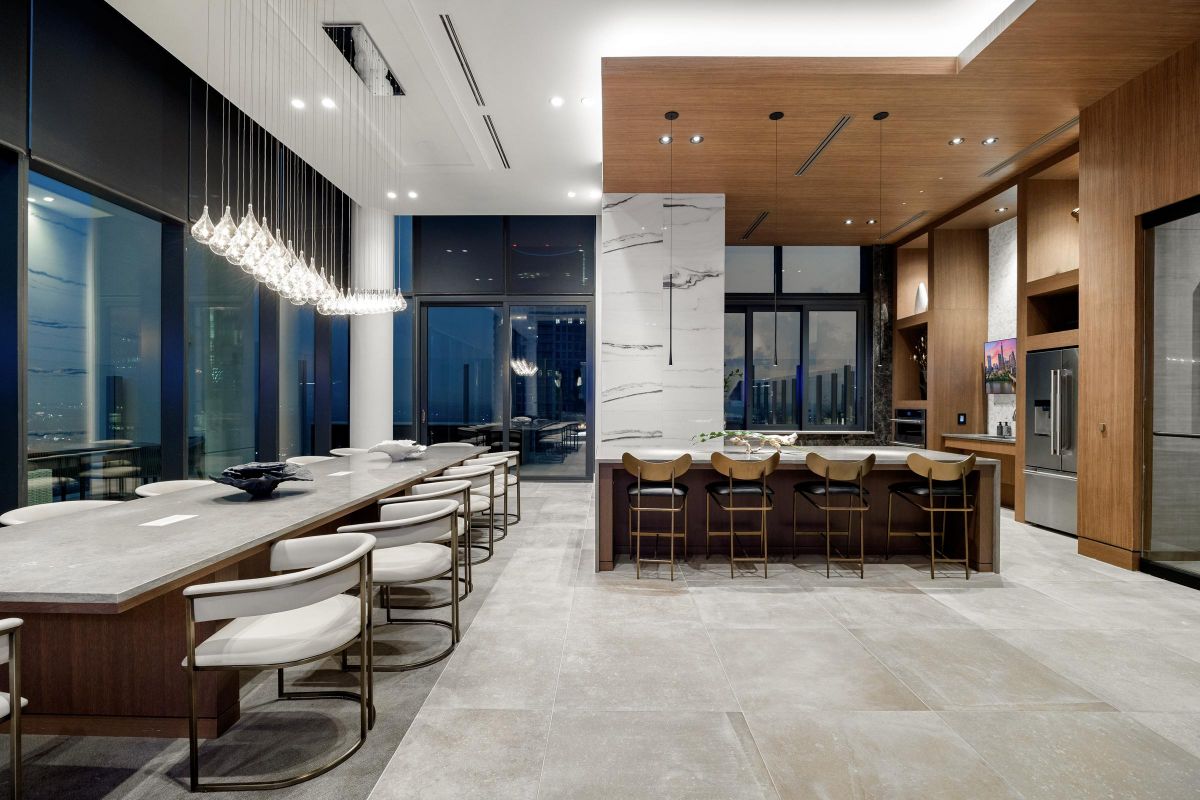Modern kitchen and dining area with large windows, an island, bar stools, and pendant lighting.
