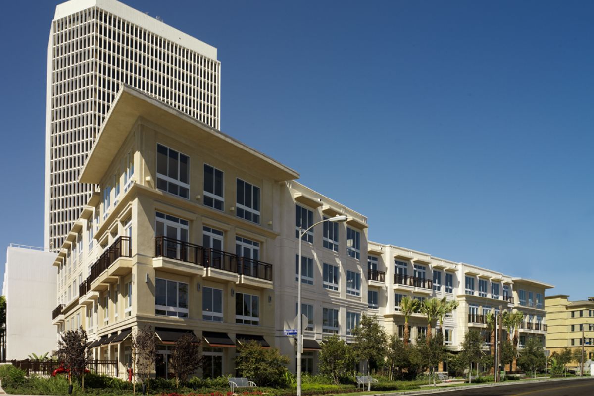 Modern apartment complex with balconies and large windows, with a tall office building in the background.