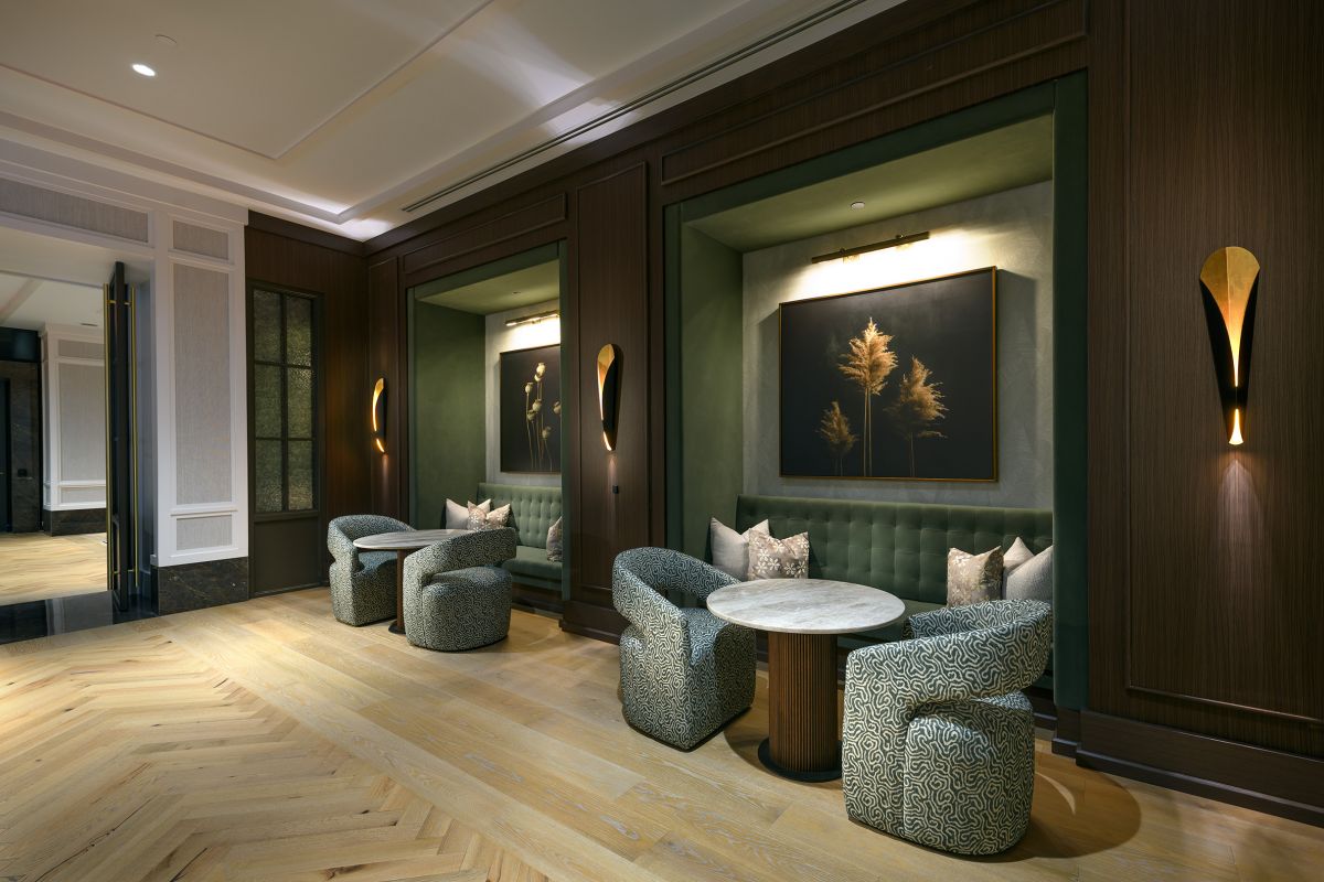 Elegant Hanover lounge with green tufted seating, round tables, patterned chairs, and modern wall art near Buffalo Bayou.