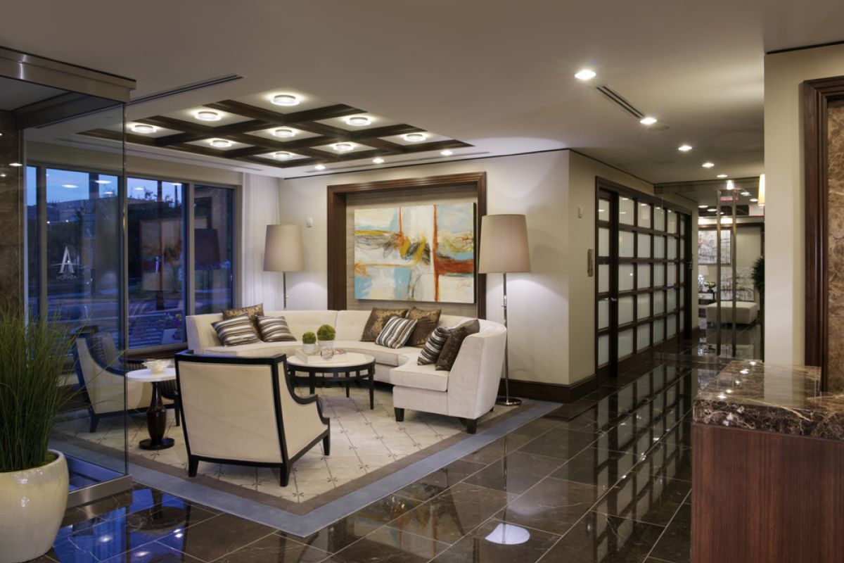 Modern office lobby with white sofas, abstract art, large lamps, and glossy marble floors.