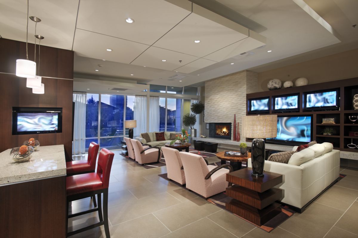Modern open living room with red chairs, white sofa, fireplace, and multiple screens on the wall.