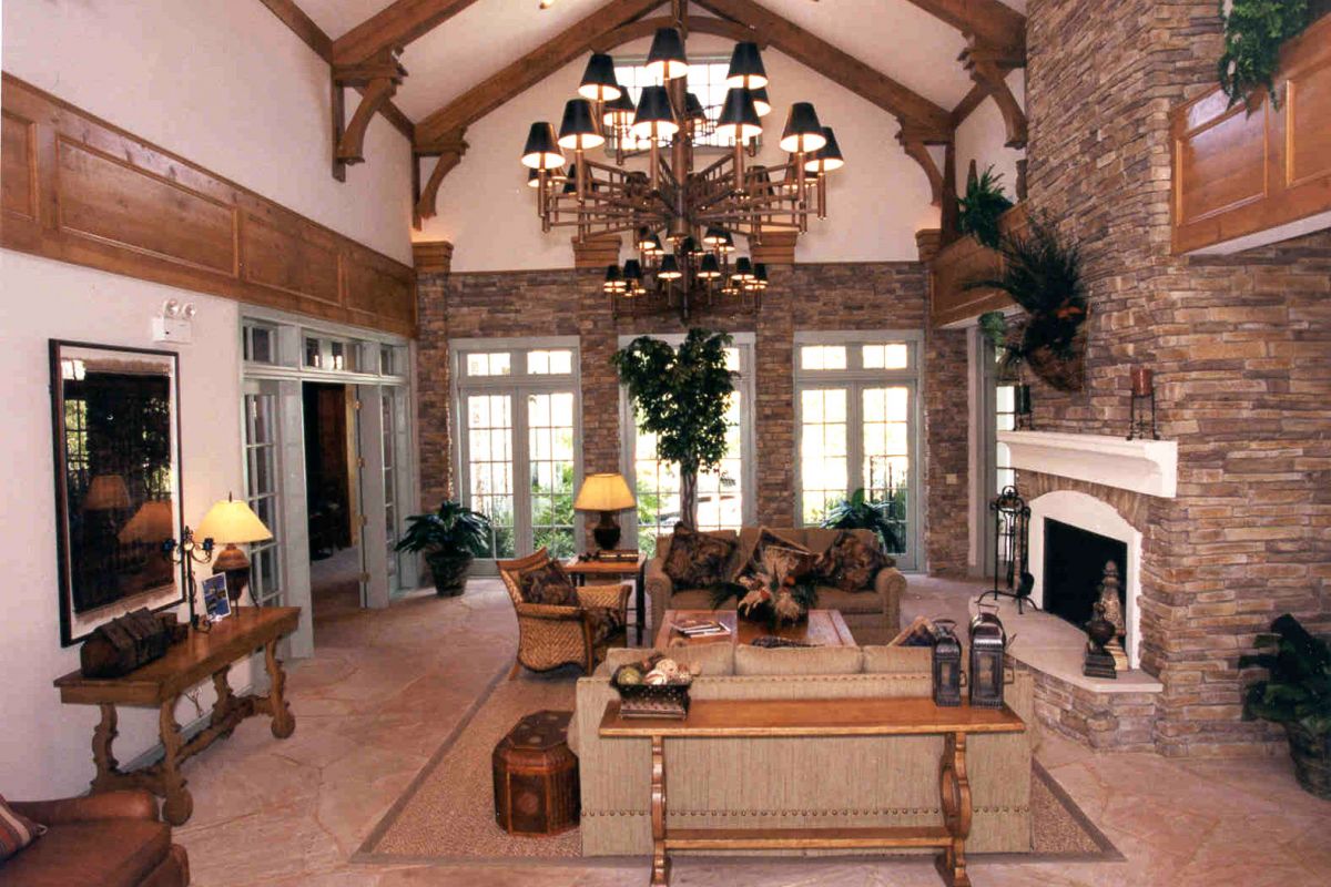 A spacious living room with high ceilings, stone fireplace, large windows, and cozy seating at Churchill on the Park.