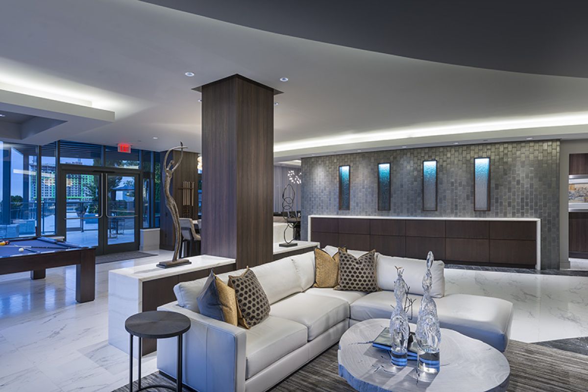 Modern hotel lobby with a white sectional sofa, marble floors, and contemporary decor.