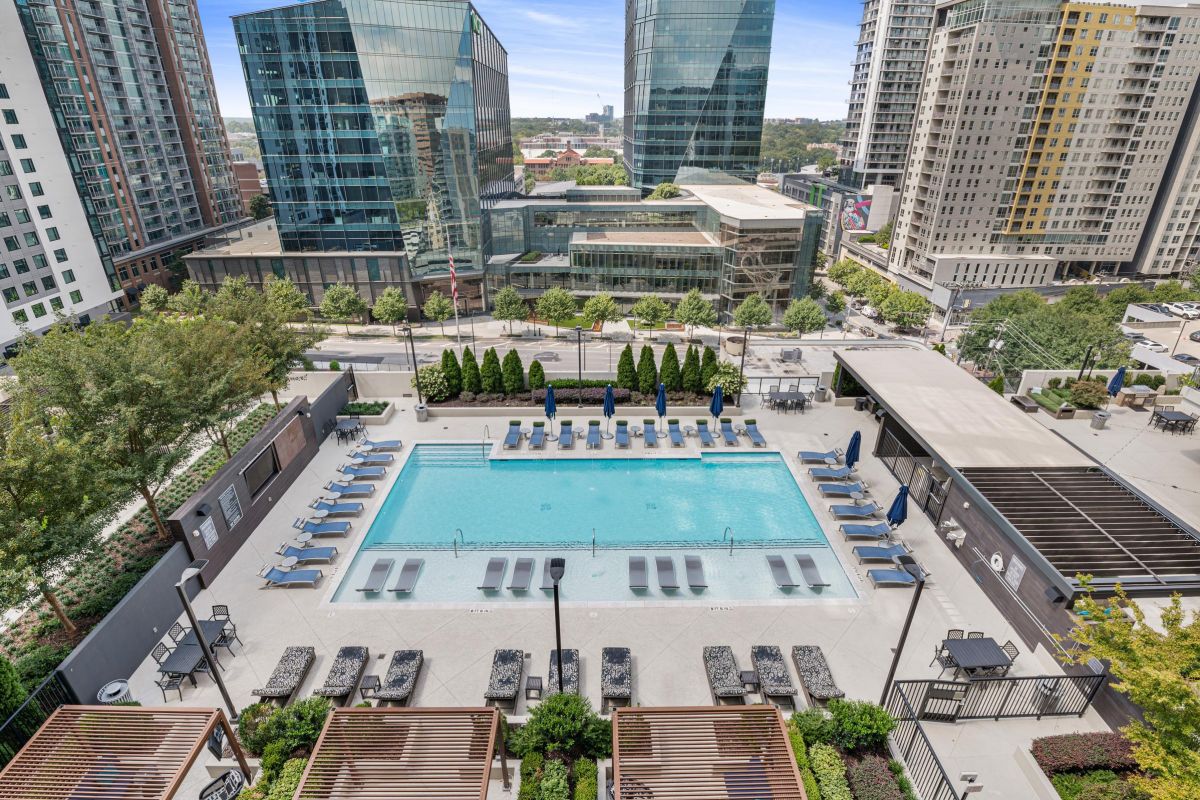 A rooftop pool surrounded by lounge chairs and city skyscrapers in the background.