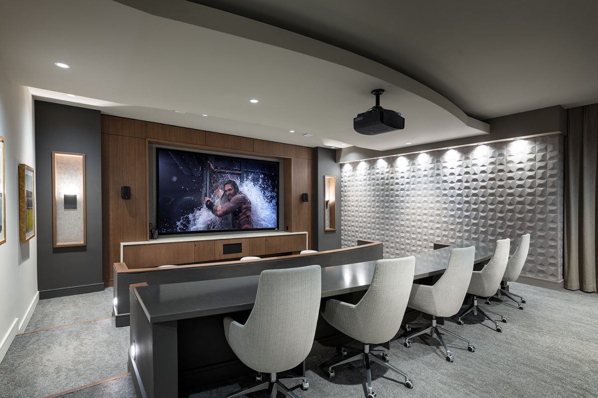 Modern home theater room with a large screen, office chairs, and a textured accent wall at Hanover Warner Center.