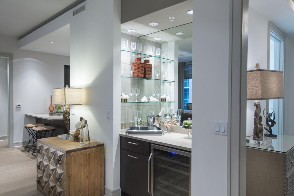 Hanover Company Modern home interior with a minibar, a wooden cabinet with lamps, and a hallway with soft lighting.