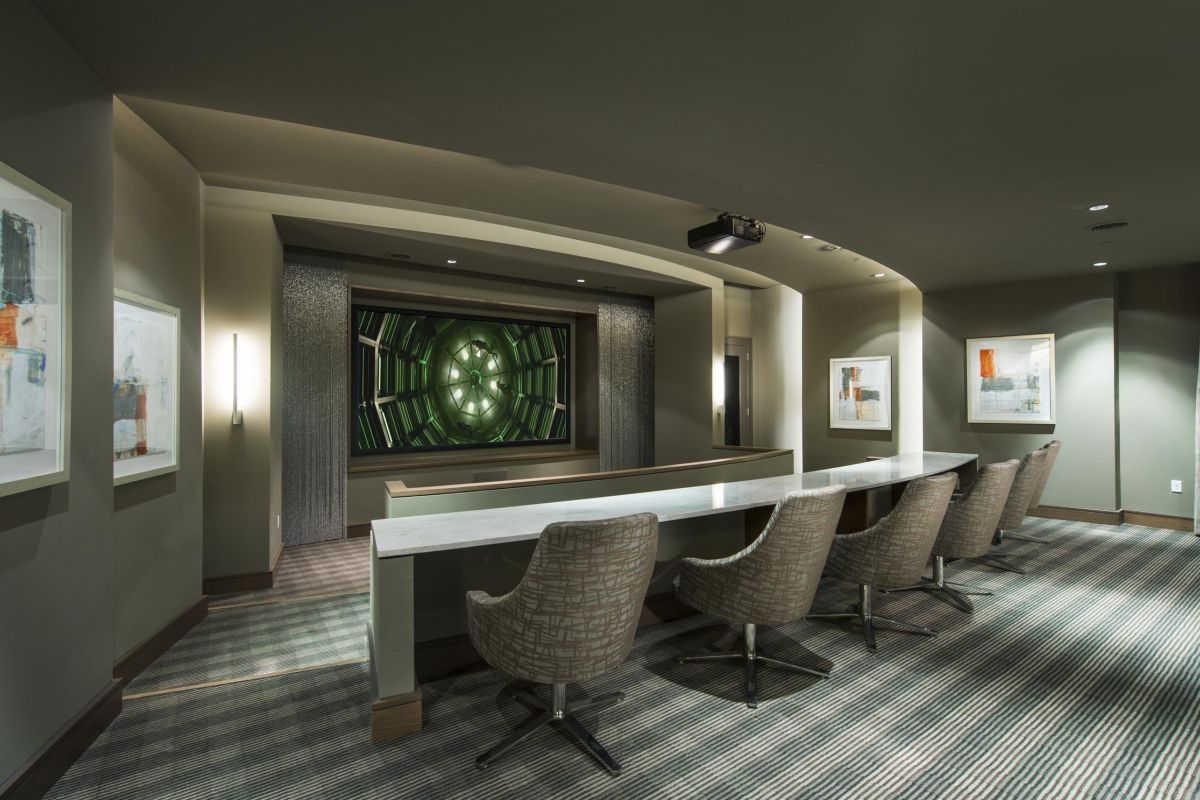 Modern home theater with gray chairs, a large screen, and abstract wall art in a dimly lit room.