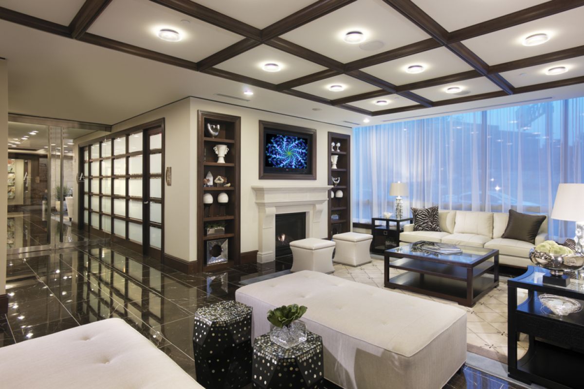 Modern living room with white sofas, a fireplace, TV, glass decor shelves, and large windows with sheer curtains.