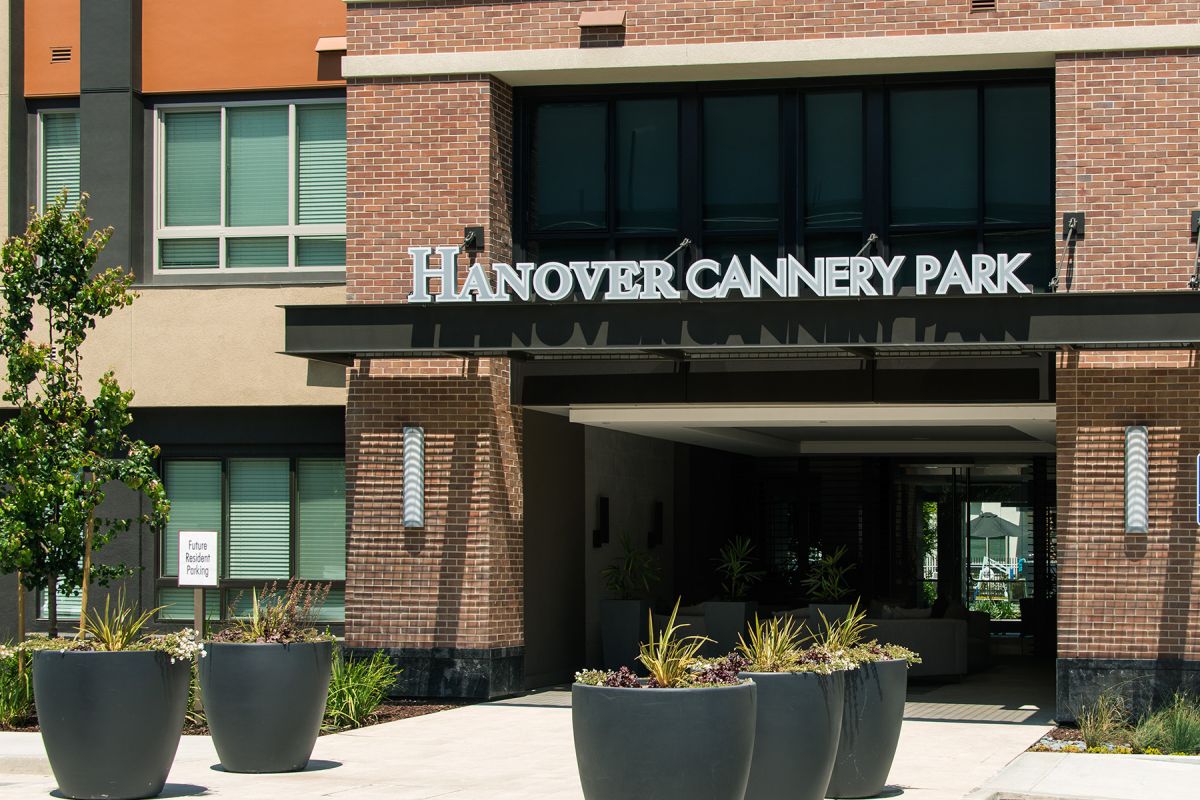 Entrance of Hanover Cannery Park building with large potted plants and a brick facade.