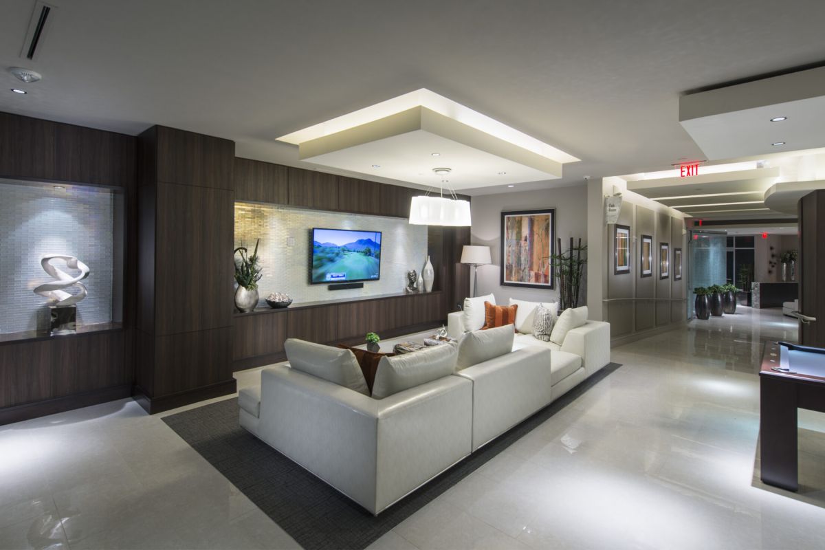Modern living room with white sofas, wall-mounted TV, and elegant lighting in a sleek, stylish interior space.