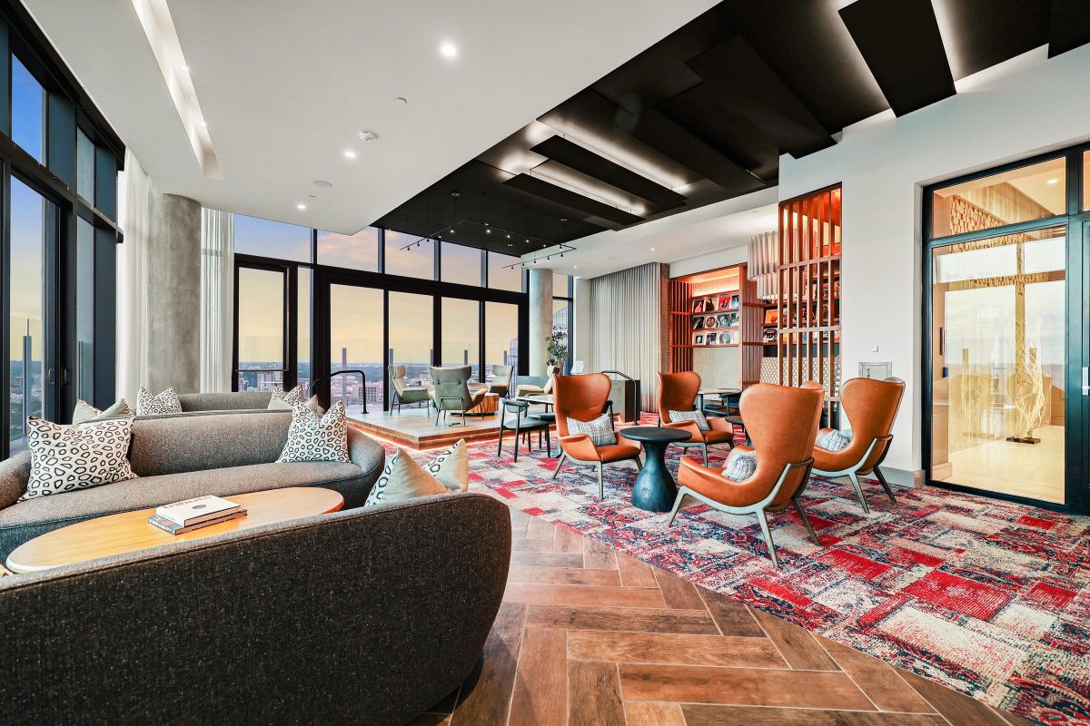 Modern, spacious lounge with large windows, stylish furniture, and a sunset view.