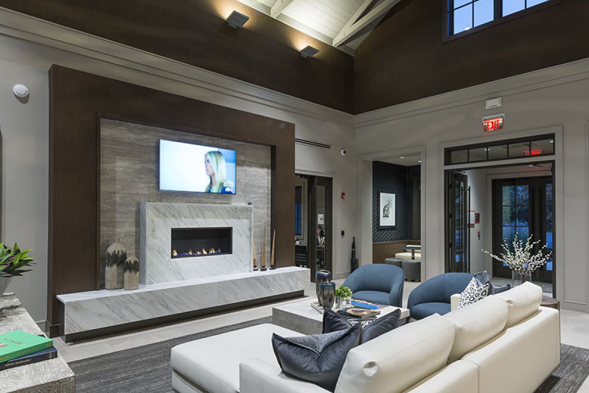 Modern living room with a white sectional sofa, fireplace, TV, and high vaulted ceiling with exposed beams.