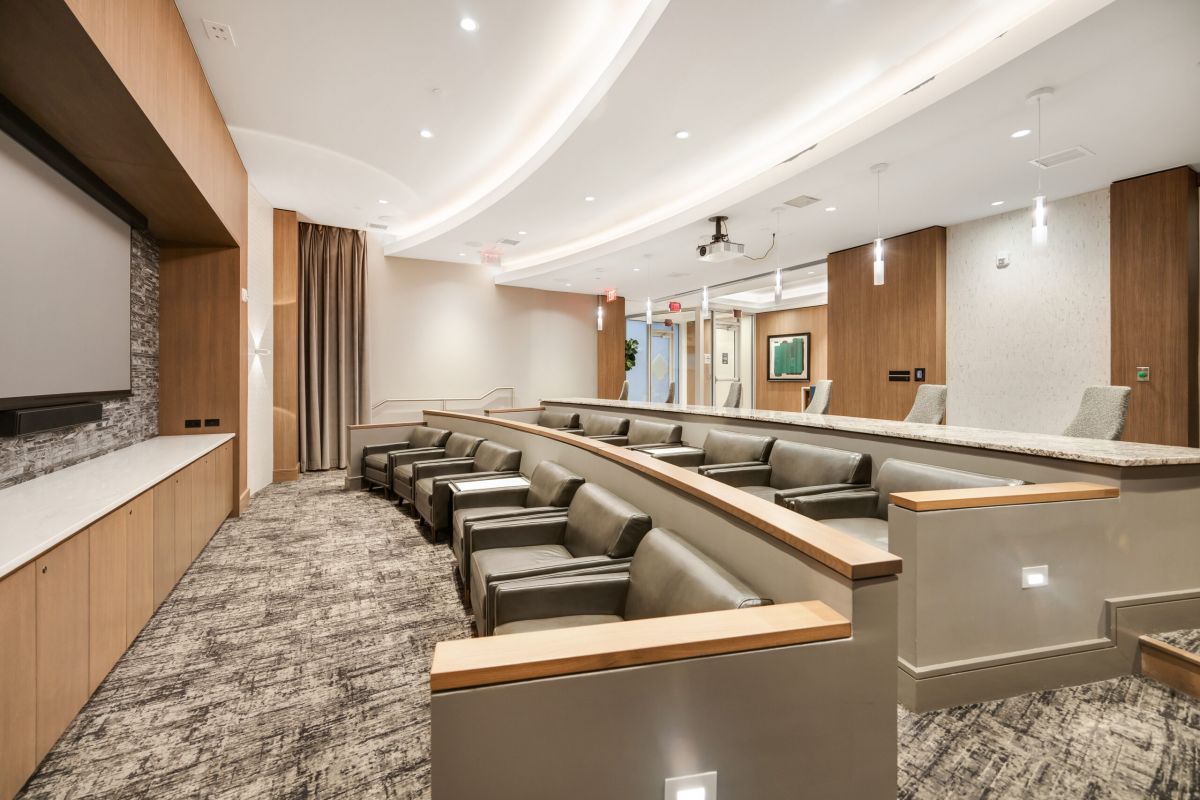 Modern conference room with tiered seating, a large screen, and neutral-toned decor.