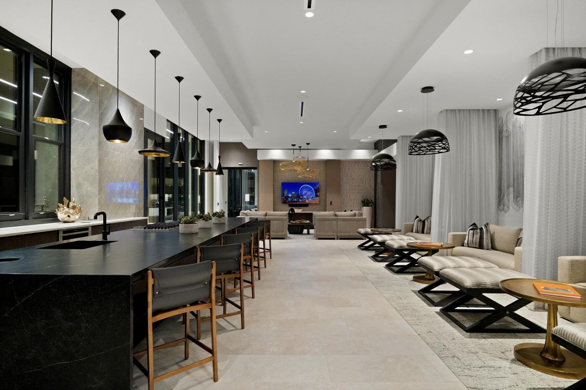 Modern lounge with bar, seating area, and overhead lights. A TV and fireplace are in the background.