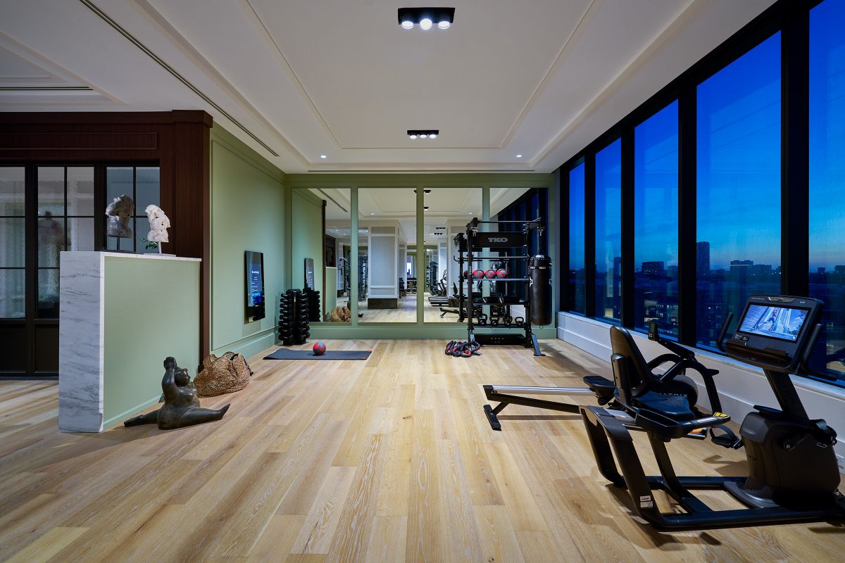 Modern gym with exercise equipment, wooden floor, and city sunset views—perfect for Hanover apartments near Buffalo Bayou.