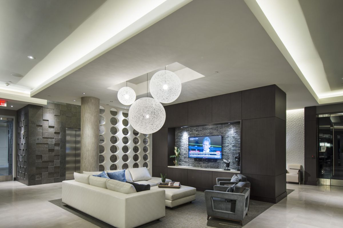 Modern lounge with white sofas, large round pendant lights, and a TV mounted on a dark accent wall.