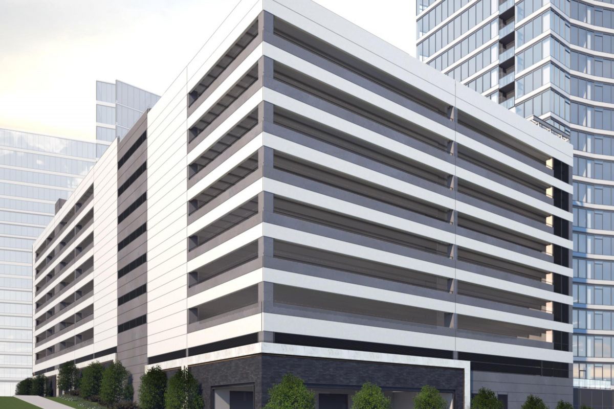 Modern multi-story parking garage with horizontal stripes, surrounded by greenery and adjacent to tall buildings.