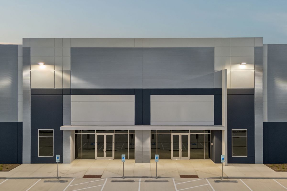 Modern, empty commercial building with large windows, blue and white facade, and an empty parking lot.